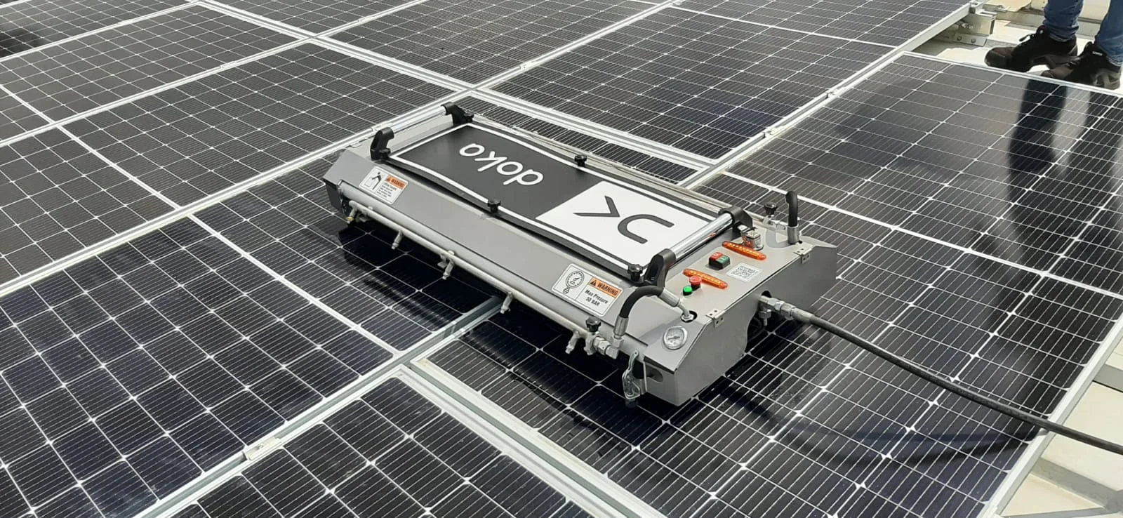 FK-series solar panel cleaning robot deployed on a rooftop PV system with operator
